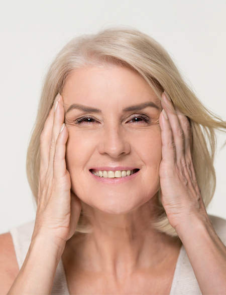 Mujer senior sonriendo estirándose el rostro