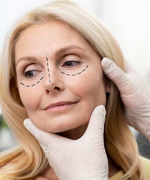 Manos de cirujano sosteniendo la cara de una mujer preparada para cirugía estética facial