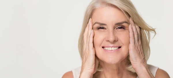 Mujer senior sonriendo estirándose el rostro