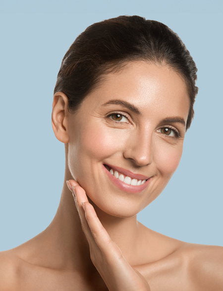 Mujer joven con piel saludable sonriendo y tocándose la cara